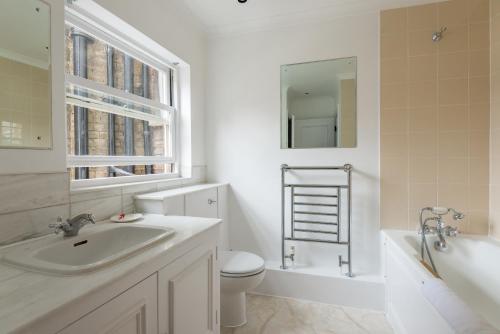a bathroom with a sink and a toilet and a tub at One bedroom High street kensington Apartment in London