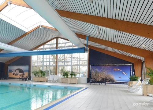 a large swimming pool with a large screen in a building at Het Dobbertje, charmant houten huisje in Sint Maartensvlotbrug