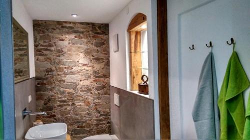 a bathroom with a toilet and a stone wall at Ferienwohnung Maringer in Ungenach