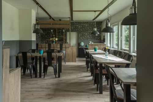 uma sala de jantar com mesas, cadeiras e janelas em Welt Lodge em Altenau