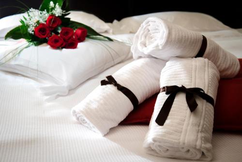 a pair of towels on a bed with roses at UNAHOTELS Villa dei Platani Foligno in Foligno