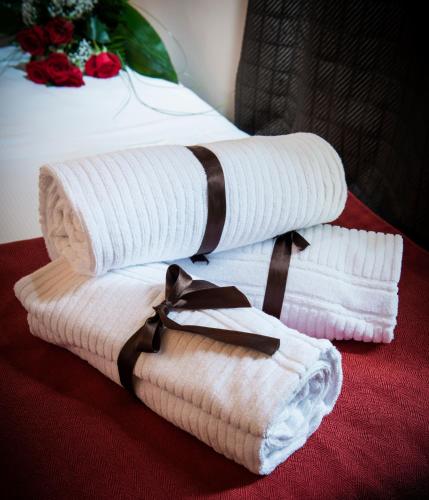 a stack of towels with a tie on a bed at UNAHOTELS Villa dei Platani Foligno in Foligno