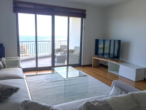 un soggiorno con divano e tavolino in vetro di The Seaside Apartment a Funchal