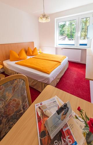 a bedroom with a bed and a table with a magazine at Hotel Waldidyll in Baabe
