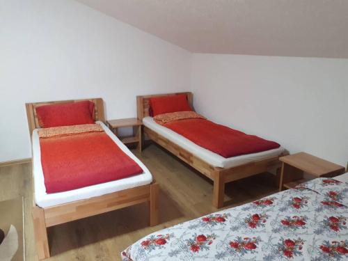 um quarto com duas camas com lençóis vermelhos e brancos em Apartmani Tajra em Visoko