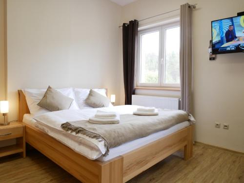 a bedroom with a bed with white sheets and a window at Penzion Adéla in Rožnov pod Radhoštěm
