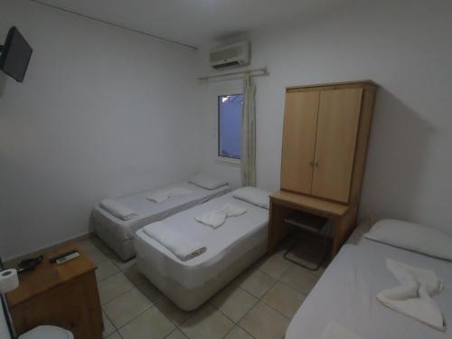 a room with two beds and a cabinet and a window at Merhaba Pansiyon in Bodrum City