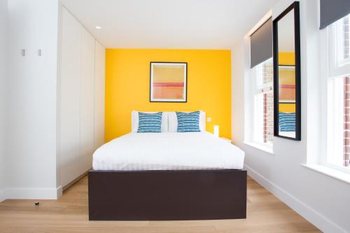 a bedroom with a bed and a yellow wall at Chapel Market Serviced Apartments by Concept Apartments in London