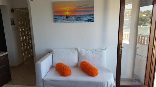 a white couch with two orange pillows in a room at Apartmani Marenda in Supetarska Draga