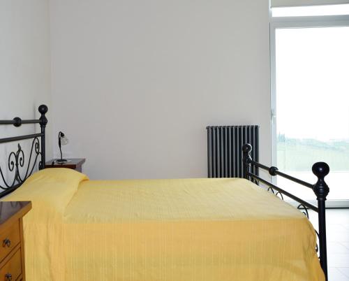 Cama amarilla en habitación con ventana en Appartamento Malvarosa, en Colonnella