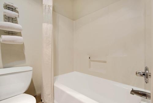 a white bathroom with a toilet and a shower at Super 8 by Wyndham Riverside/Kansas City in Kansas City