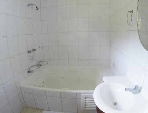 La salle de bains blanche est pourvue d'une baignoire et d'un lavabo. dans l'établissement Hotel Imperador Caldas, à Santo Amaro da Imperatriz