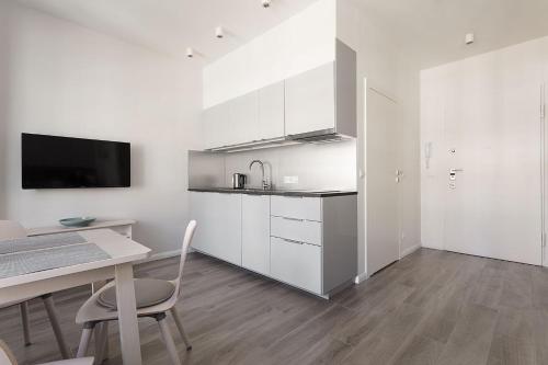 グダニスクにあるVIU Cinnamon Apartmentの白いキャビネット、テーブルと椅子付きのキッチンが備わります。