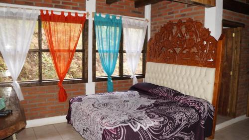 a bedroom with a bed and windows with curtains at Rincón del Bosque in Mazamitla