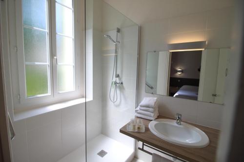 a white bathroom with a sink and a shower at Logis Hotel restaurant des Thermes in Lamalou-les-Bains