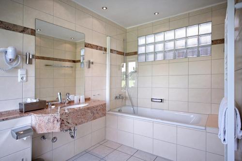 a bathroom with a tub and a sink at Hotel Perekop in Berdorf