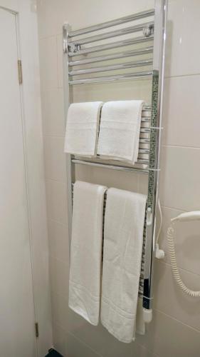 un portasciugamani con asciugamani bianchi in un bagno di Apartman Mia a Belgrado