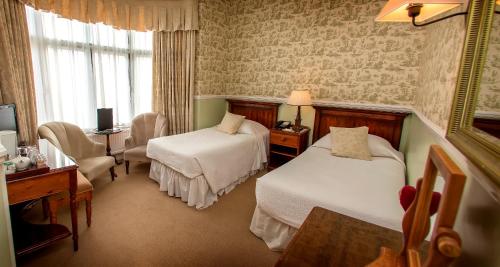 a hotel room with two beds and a desk at Dunoon Hotel in Llandudno