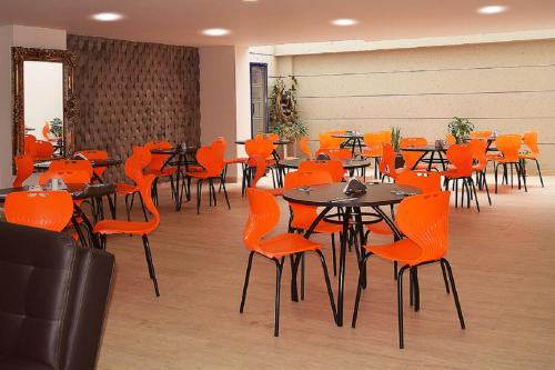 un restaurante con mesas y sillas naranjas en una habitación en Hotel Avanty, en Ipiales
