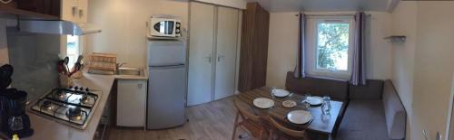 une petite cuisine avec une table et un réfrigérateur dans l'établissement Mobil-home 4 pers dans Camping 4 étoiles La Palmyre, à La Palmyre