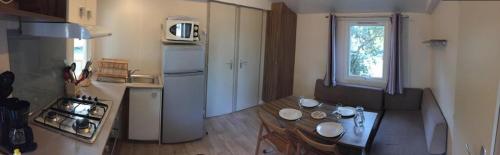 a small kitchen with a table and a refrigerator at Mobil-home 4 pers dans Camping 4 étoiles La Palmyre in La Palmyre