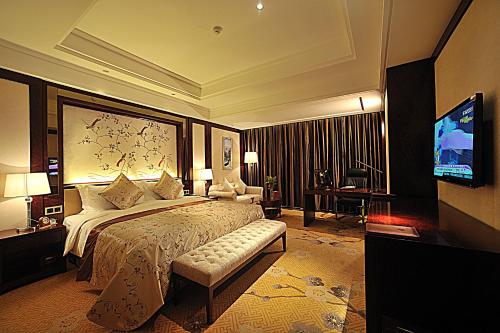 TaizhouにあるTai Zhou International Jinling Hotelのベッドとテレビが備わるホテルルームです。