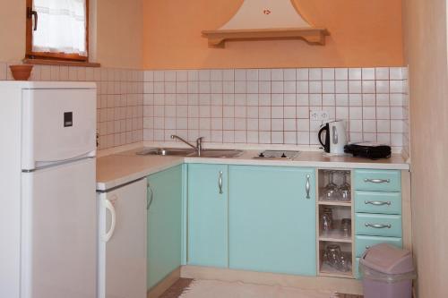 La cuisine est équipée de placards bleus et d'un réfrigérateur blanc. dans l'établissement Villa Visnjan Residence 2, à Višnjan