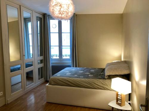 une chambre avec un lit et un lustre dans l'établissement Appartement VALENTINE, à Trouville-sur-Mer
