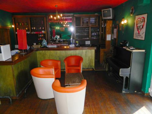 - un bar avec des chaises orange et un piano dans la chambre dans l'établissement Villa Park, à Mostar