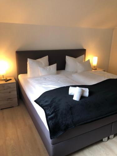 Una cama con una manta negra y dos toallas. en Sanosueno 1, en Sonthofen
