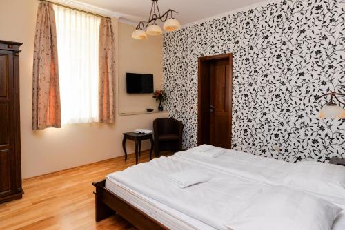 a bedroom with a bed and a black and white wallpaper at Althaus Vendégház in Németkér