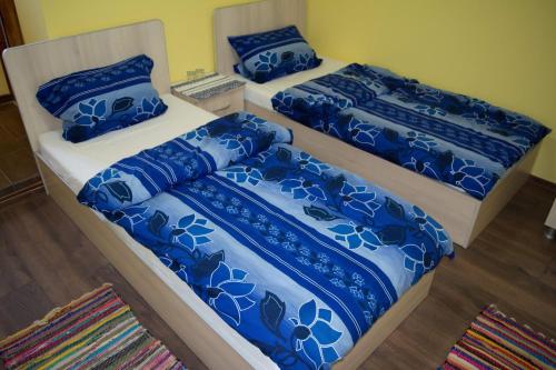two beds in a room with blue and white sheets at Casa Ana in Biertan