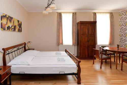 a bedroom with a bed and a table and chairs at Althaus Vendégház in Németkér