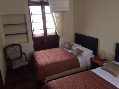 a bedroom with two beds and a chair and a window at Casa Vista Hermosa Quito in Quito