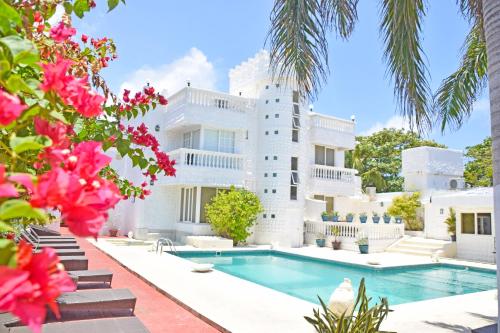 um grande edifício branco com uma piscina e flores cor-de-rosa em Le Castel Blanc Hotel Boutique em San Andrés