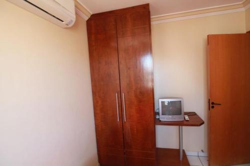 1 dormitorio con armario de madera y TV en Condominio Millenium Thermas Residence, en Caldas Novas