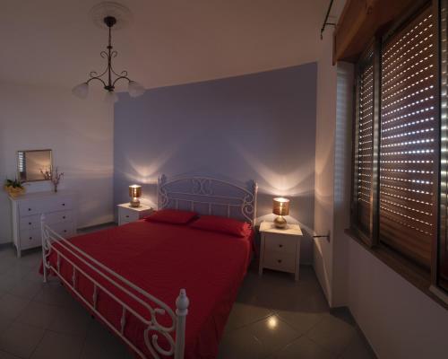 リド・マリーニにあるAppartamento Pesceのベッドルーム1室(赤いベッド1台、ナイトスタンド2台付)