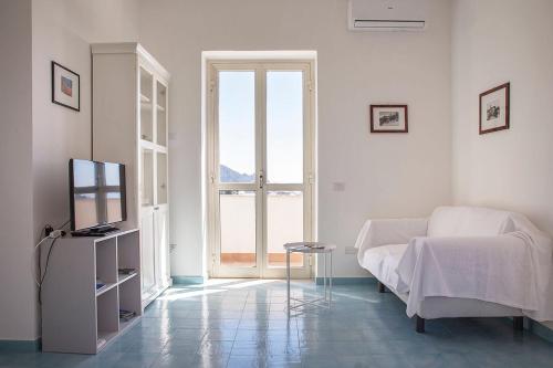 a white room with a bed and a television at Dolce Vista Apartment Amalfi Coast in Scala