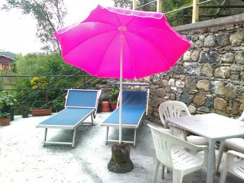 a pink umbrella and some chairs and a table and chairs at Casa dell'ulivo in Moneglia