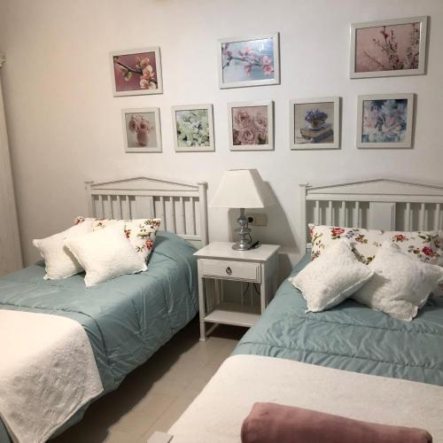 a bedroom with two beds and a lamp and pictures on the wall at La Aurora in Antigua