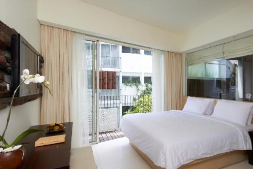 a bedroom with a large bed and a large window at The Akmani Legian in Legian