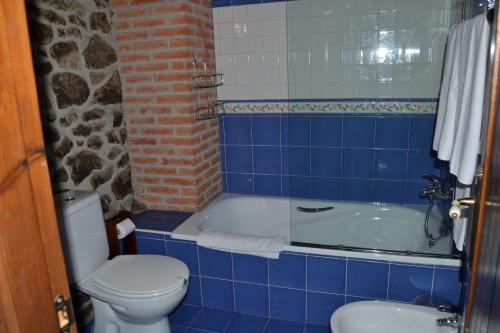 y baño de azulejos azules con aseo y bañera. en La Seronda de Redes en Bueres