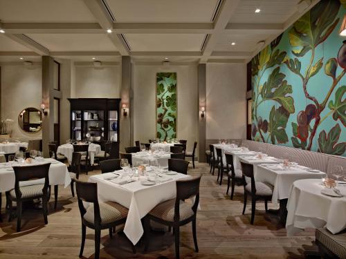 a restaurant with white tables and chairs and a painting at Delamar West Hartford in West Hartford