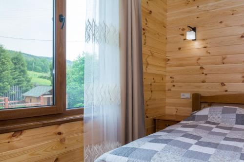 1 dormitorio con ventana en una cabaña de madera en Zolota Rybka, en Skhidnytsya