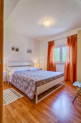 a bedroom with a large bed and orange curtains at Apartmani Prodan 2 in Fažana