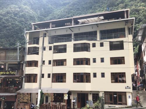 a large white building with a mountain in the background at Casa De Luz Hotel in Machu Picchu