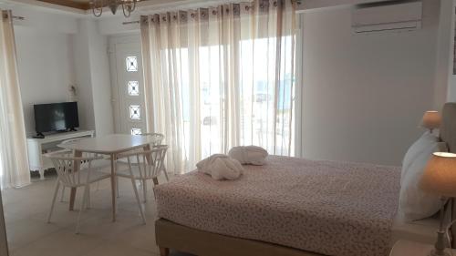 a bedroom with a bed and a table and a window at Bella Mare Luxury Apartments in Kalamaki Heraklion