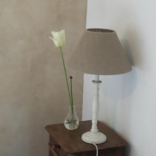 a white rose in a vase next to a lamp at Le Pas Saint Joseph in Saint Malo
