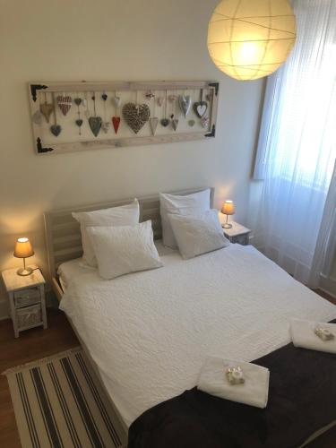 リスボンにあるThe Sunset Nestのベッドルーム1室(白いシーツとハートが壁に掛けられたベッド1台付)