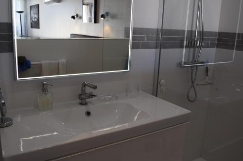 een witte badkamer met een wastafel en een spiegel bij HELIOPOLIS CAP D'AGDE VILLAGE NATURISTE in Cap d'Agde